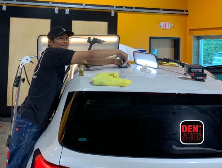 dent shop employee working on roof of vehicle